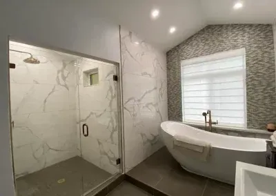 A bathroom with a tub , shower , and window.