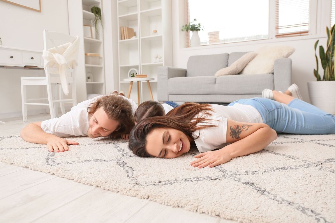 A man and a woman are laying on the floor in a living room.