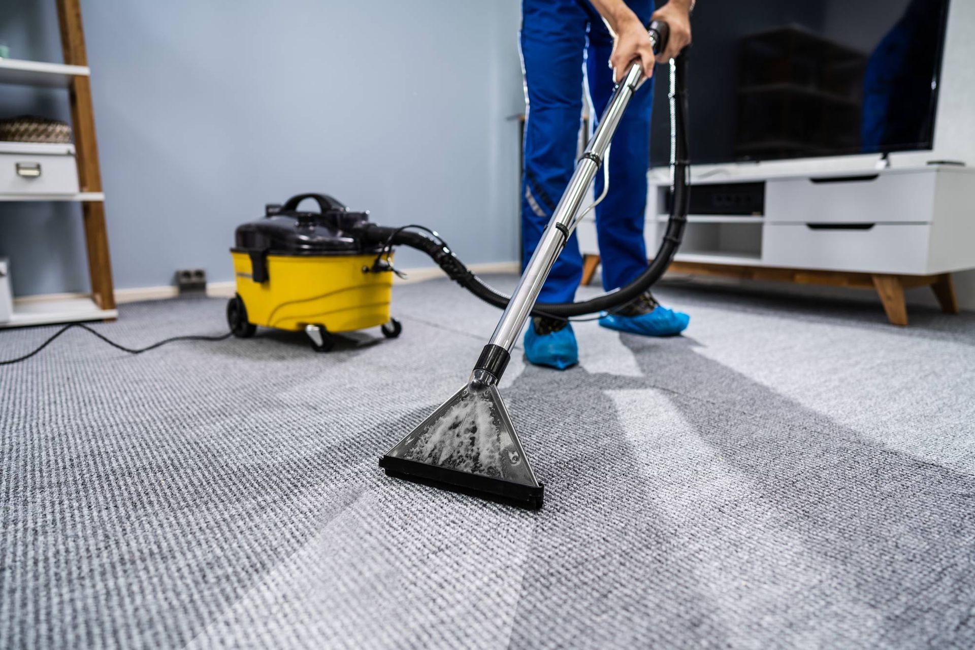 A person is using a vacuum cleaner to clean a carpet in a living room.