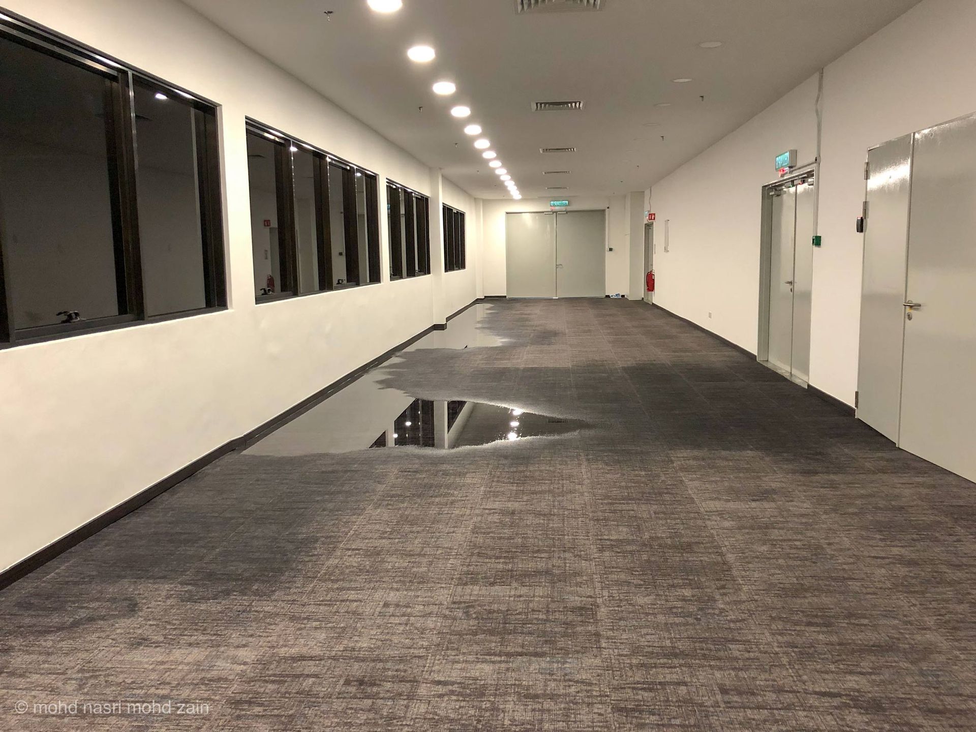 A long hallway with a puddle of water on the floor.