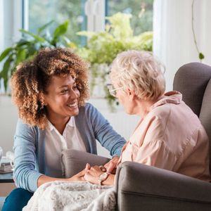 A woman is sitting in a chair talking to an older woman – Andover, MA - At Home Care