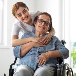 A young woman is hugging an older woman in a wheelchair – Andover, MA - At Home Care