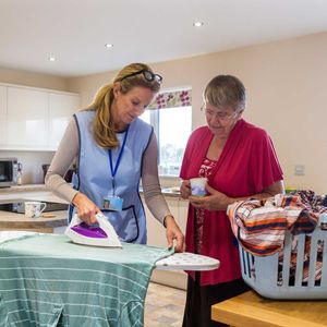 The female carer is ironing in the kitchen to help an elderly woman – Andover, MA - At Home Care