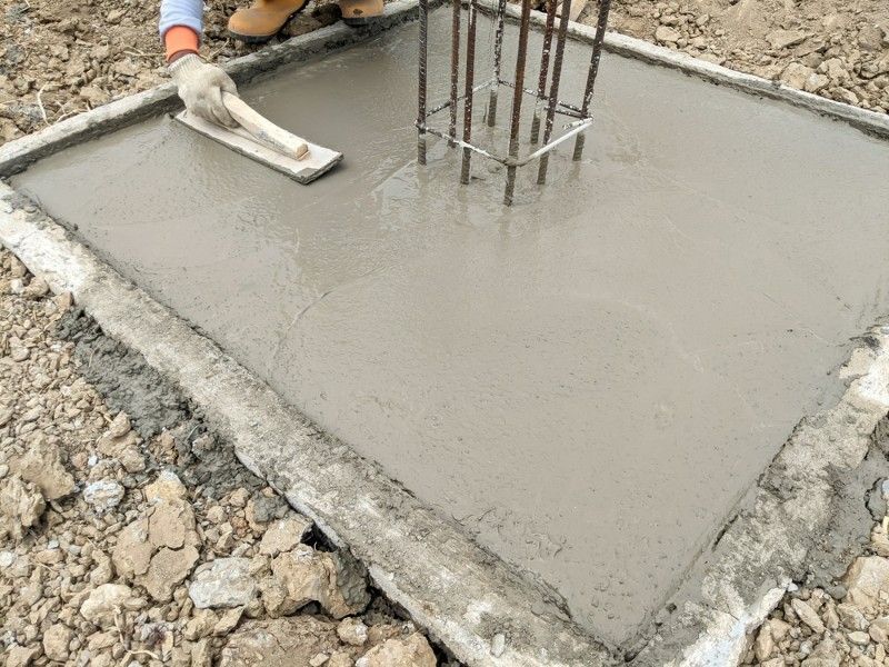 A Person is Spreading Concrete on the Ground With a Trowel — Tiga's Concreting Services In Branyan, QLD
