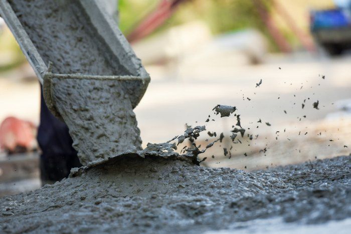 A Person is Pouring Concrete Into a Bucket on a Construction Site — Tiga's Concreting Services In Branyan, QLD