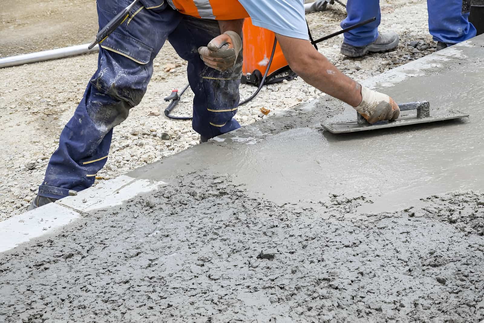 A Construction Worker is Spreading Concrete on the Ground With a Trowel — Tiga's Concreting Services In Branyan, QLD