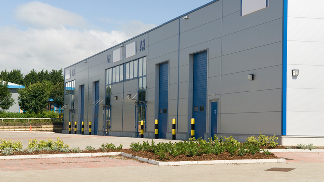 A large building with a lot of doors and plants in front of it