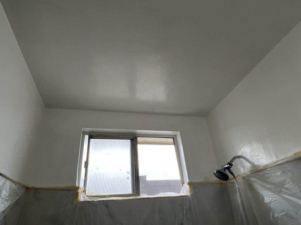 A bathroom with a window and a shower head.