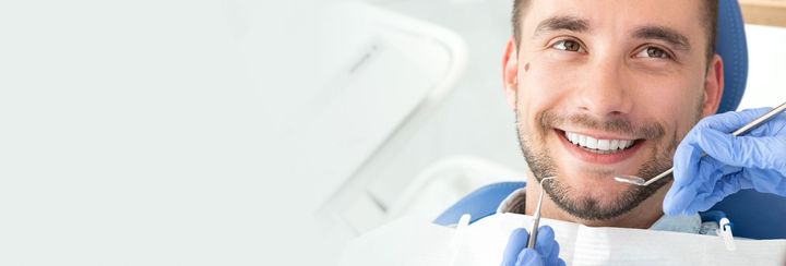 Smiling young man at the dentist, showing healthy teeth and good dental care.