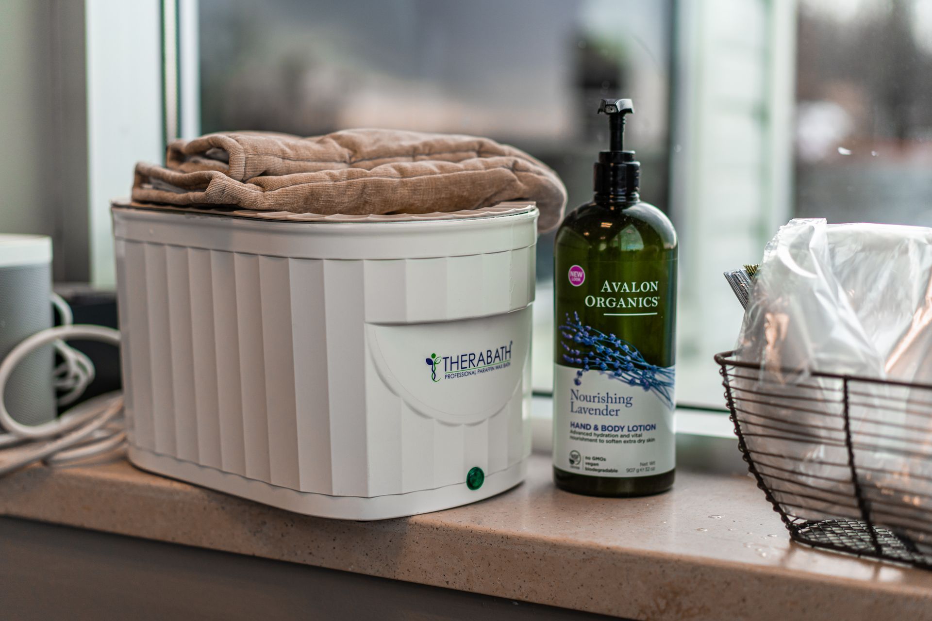 White hand towel warmer, lavender lotion, and a basket of towels on a windowsill.