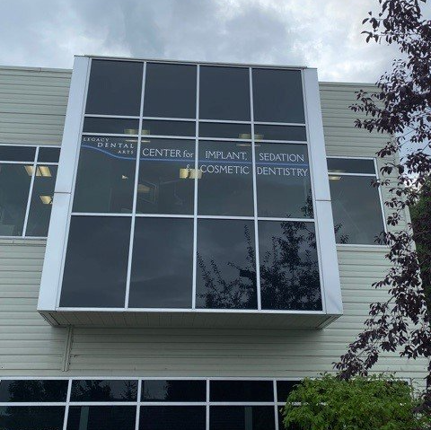 Building facade with large windows, silver trim, and signage for dental services.