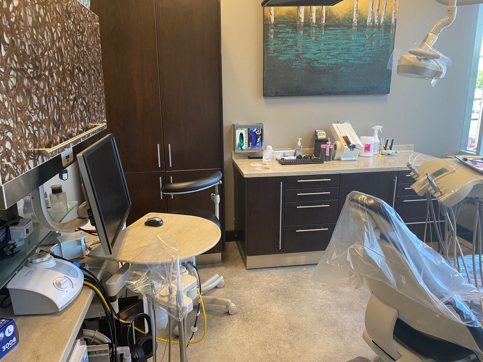 Dental examination room with chair, cabinets, and equipment.
