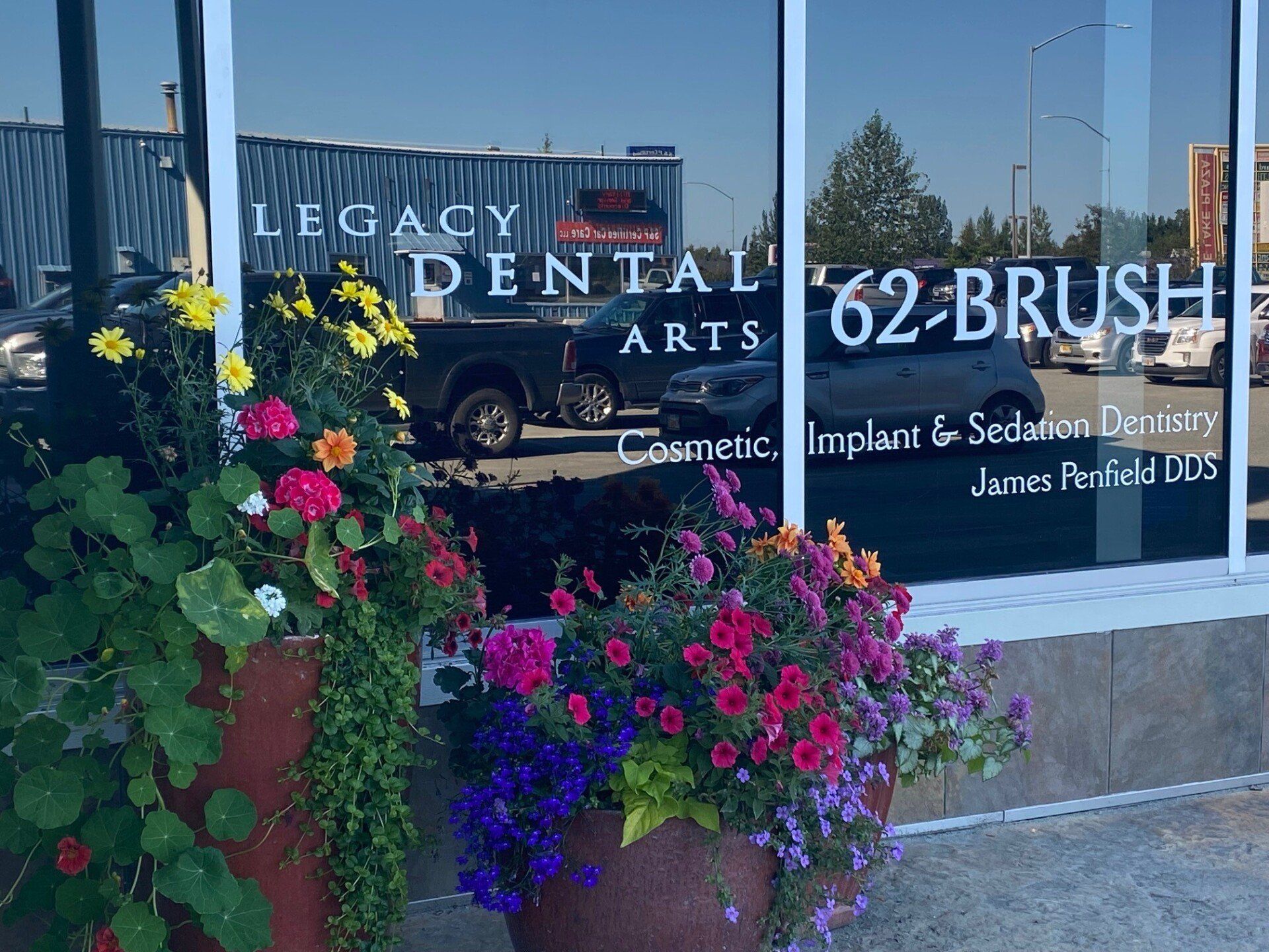 Planter of colorful flowers in front of a dental office window reading