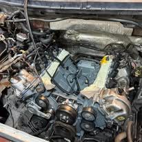 Engine bay with multiple components, including pulleys and metal tubing.