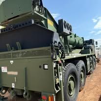 Green military vehicle with large wheels and a missile launching system.