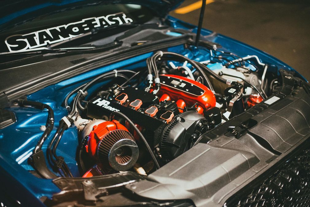 Blue car engine bay with a red intake manifold, turbocharger, and filter;