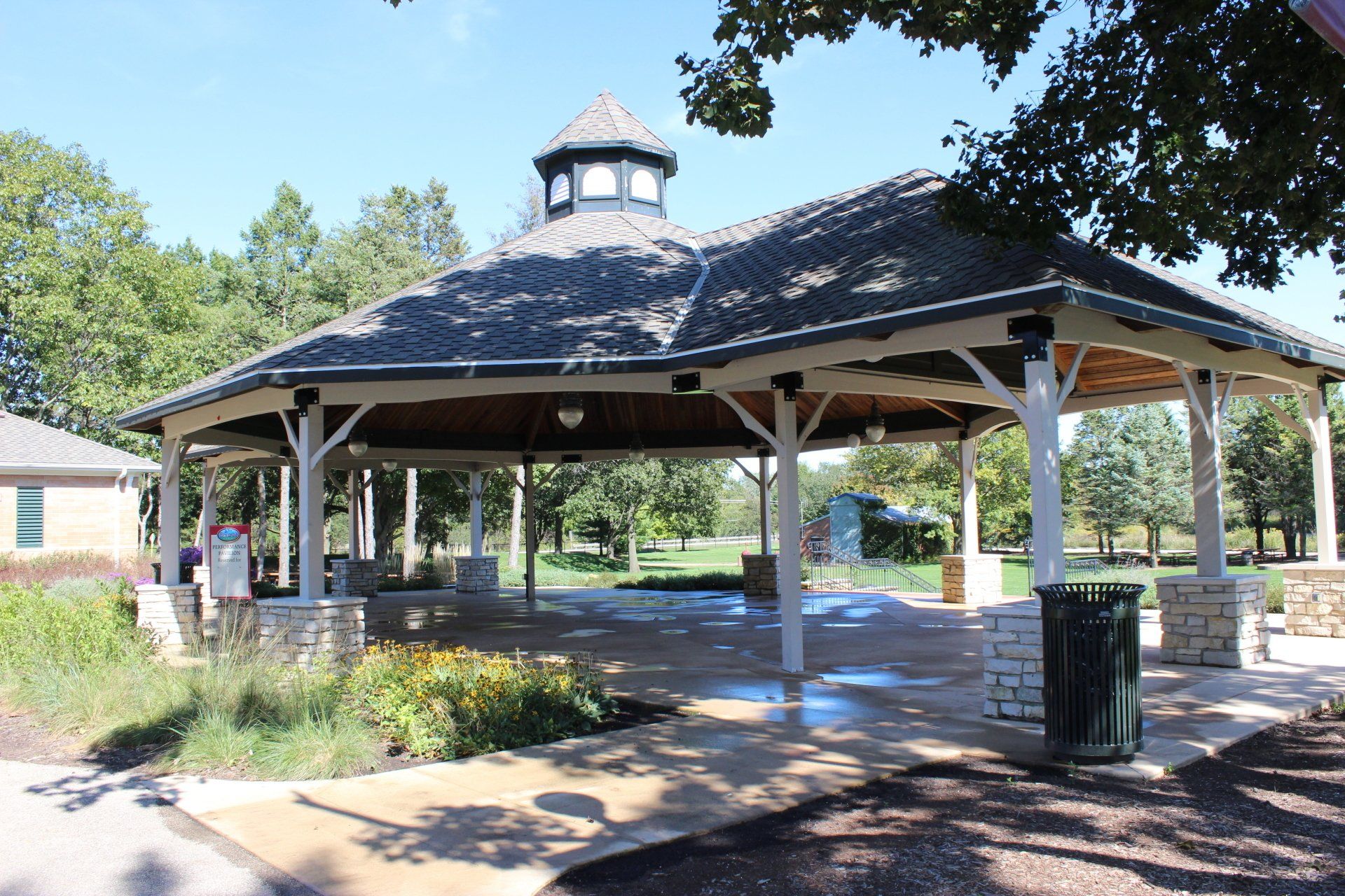 A gazebo in a park with trees in the background
