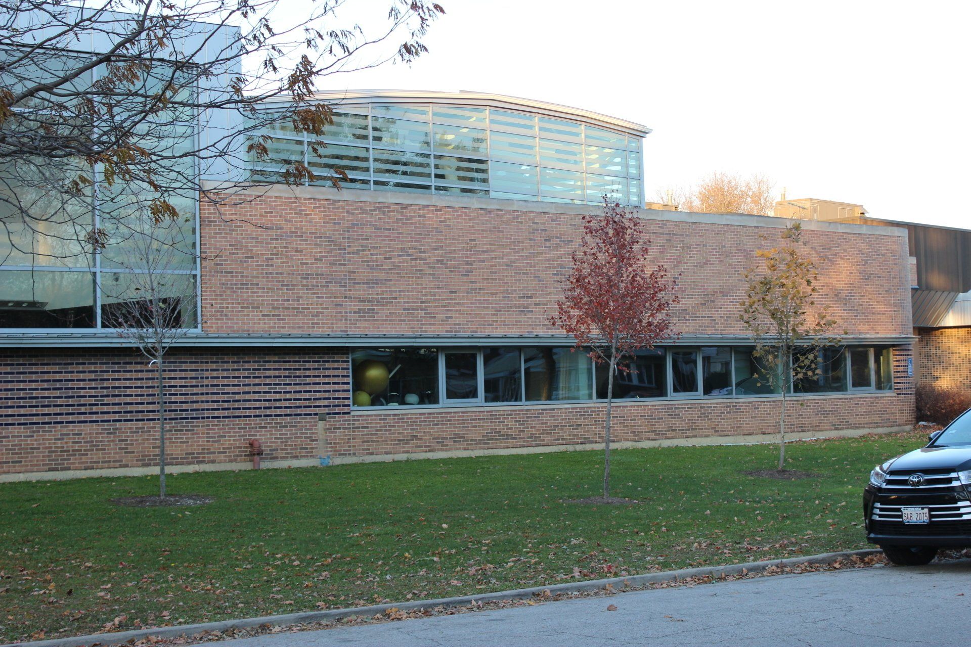 A car is parked in front of a large brick building