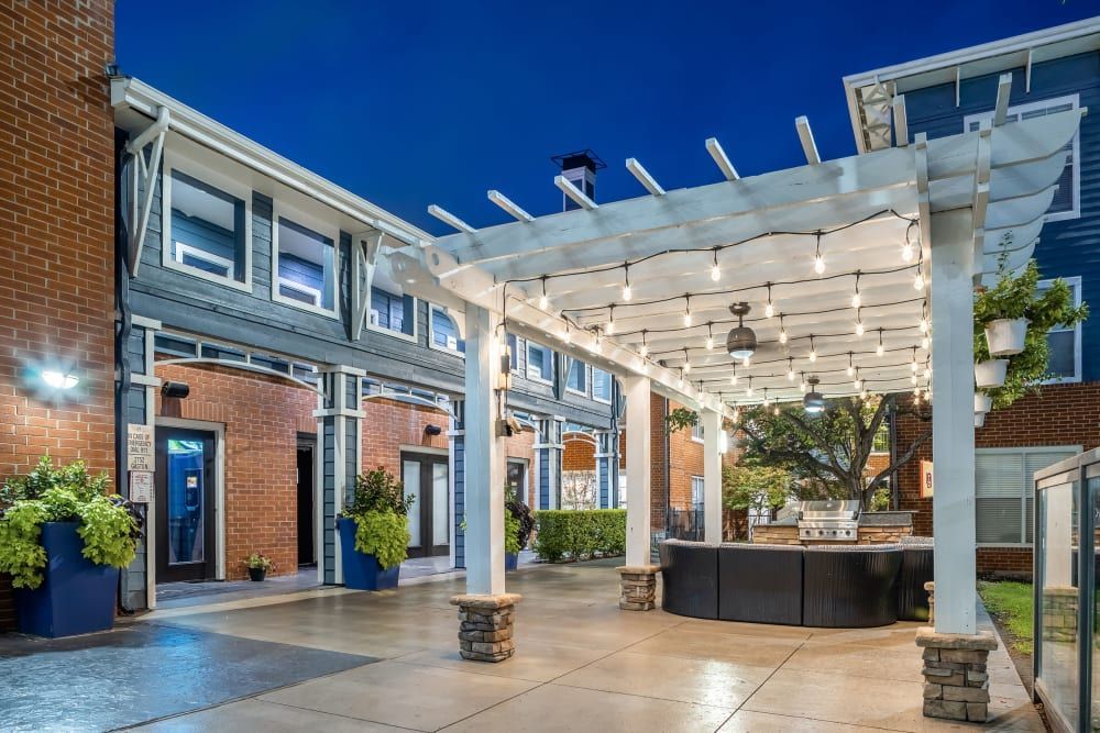a pergola with lights hanging from it in front of a building at Marquis on Gaston in Dallas, TX.