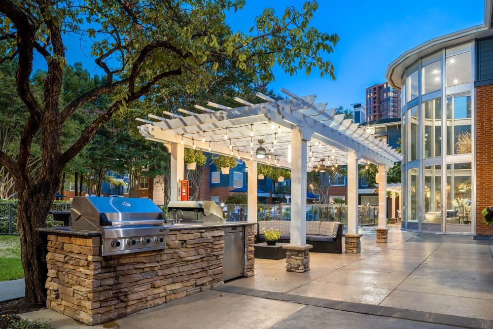 a patio with a grill and a pergola in front of a building at Marquis on Gaston in Dallas, TX.