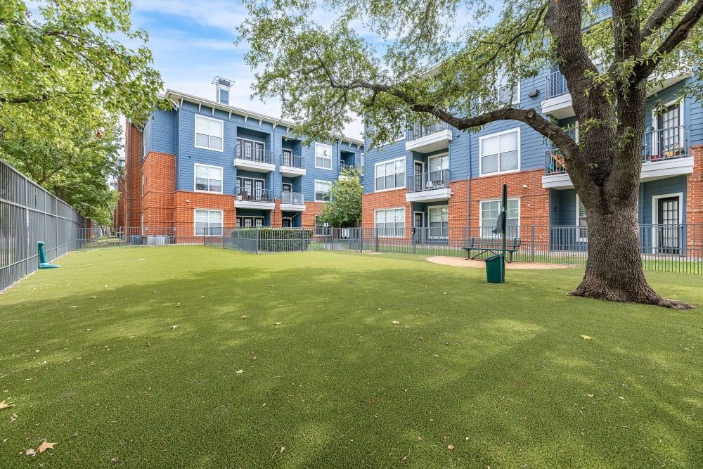 a large lawn in front of a building with a tree in the middle of it at Marquis on Gaston in Dallas, TX.