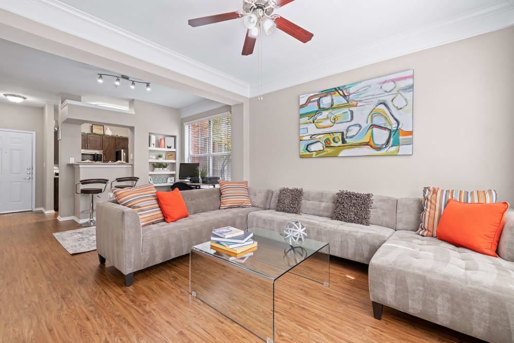 a living room with a large sectional couch and a glass coffee table at Marquis on Gaston in Dallas, TX.