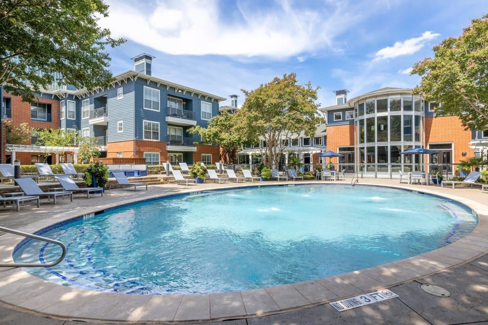 a large swimming pool surrounded by chairs and umbrellas in front of a building at Marquis on Gaston in Dallas, TX.