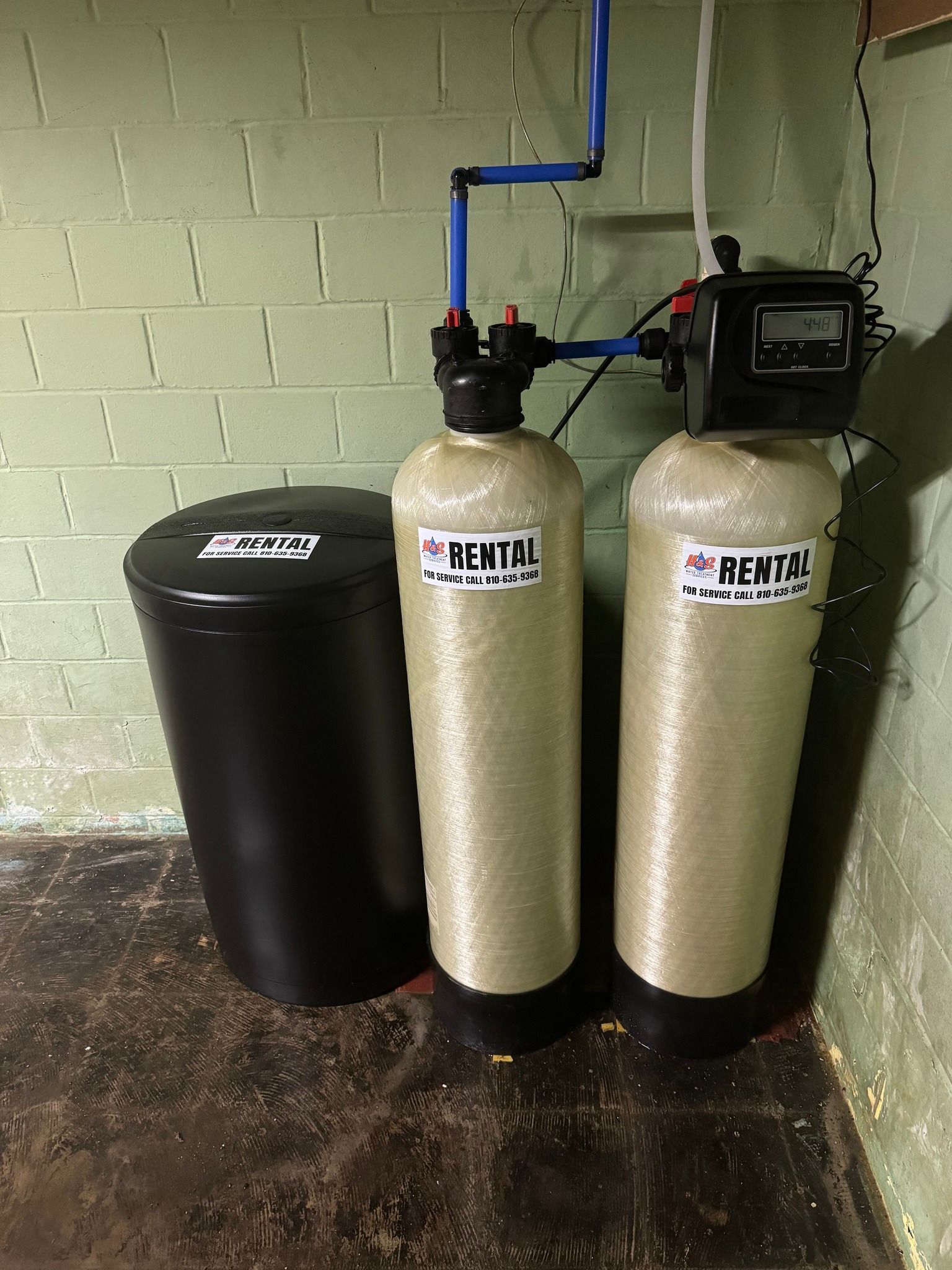 Two water filters are sitting next to each other in a basement.