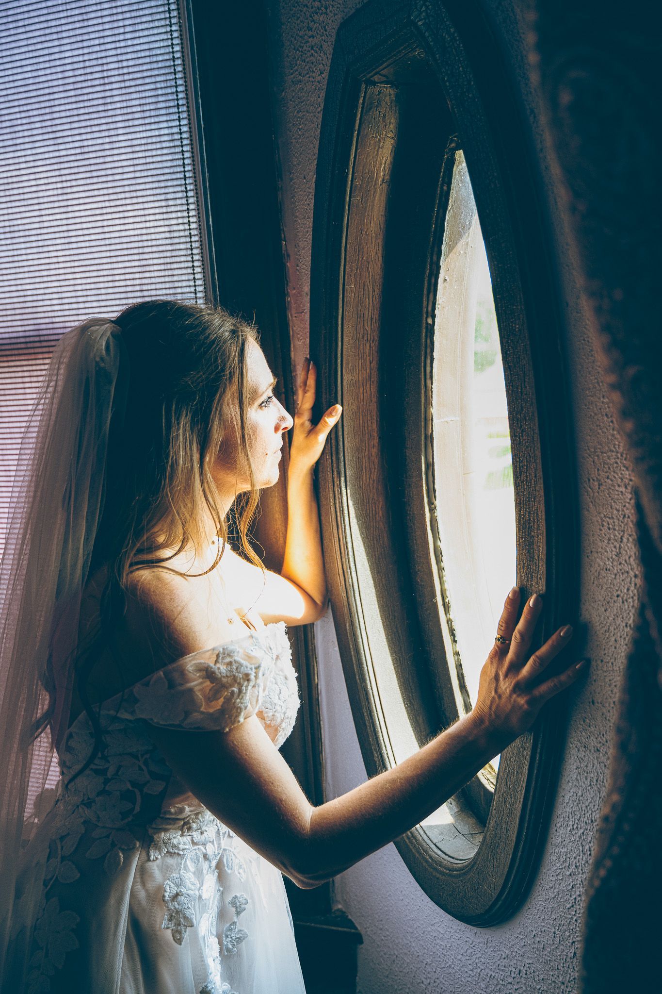 Wedding portrait of a bride looking into a window