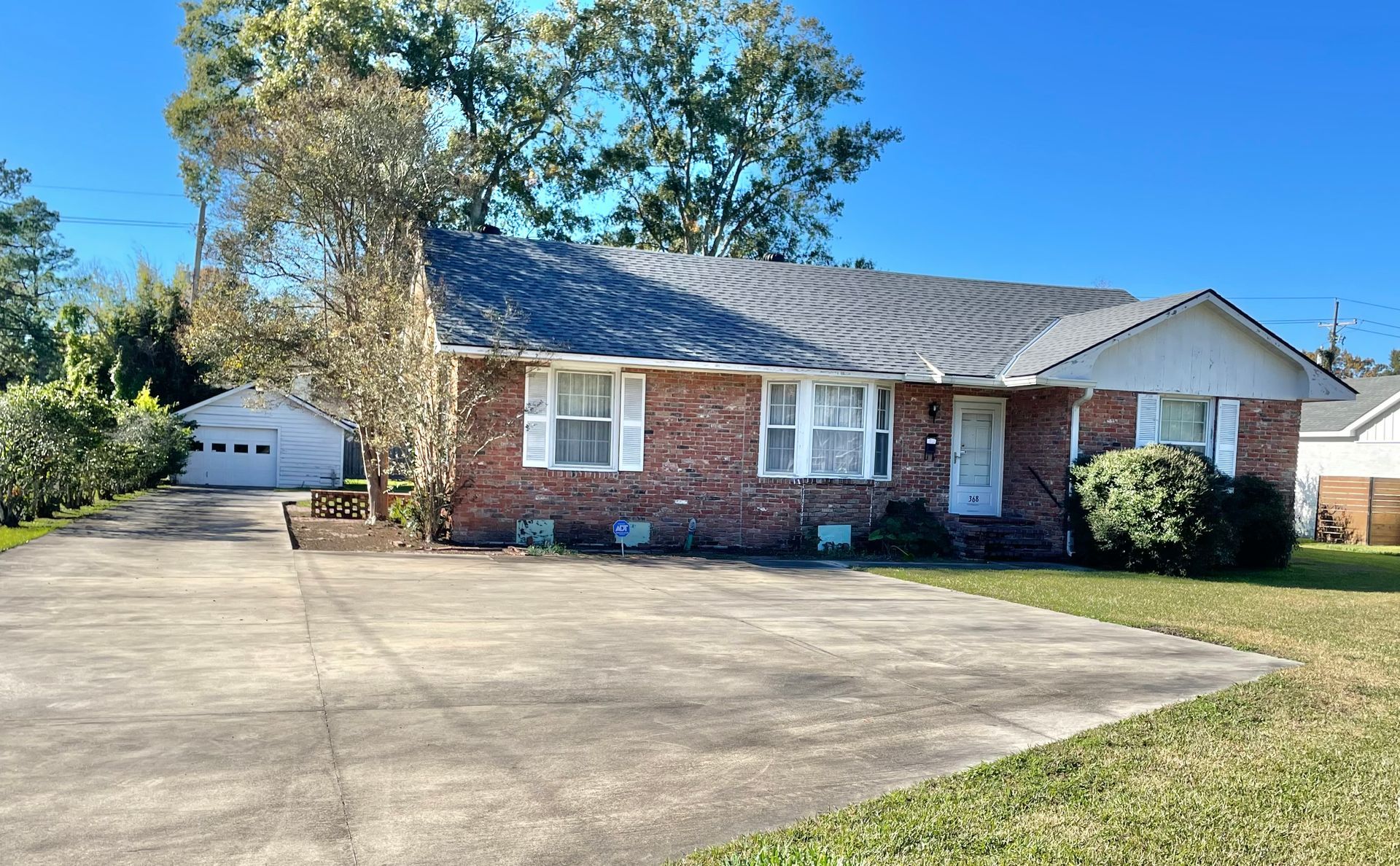 Brick house with driveway, garage, and a blue sky on a sunny day.