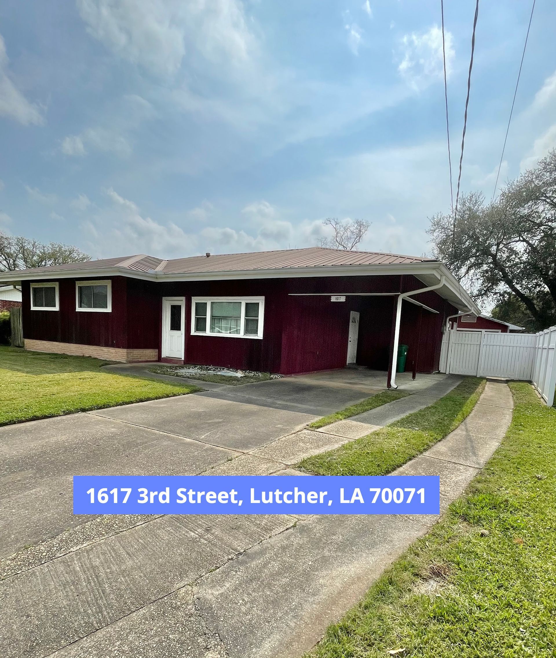 Red house at 1617 3rd Street, Lutcher, LA. Driveway, grass, cloudy sky.