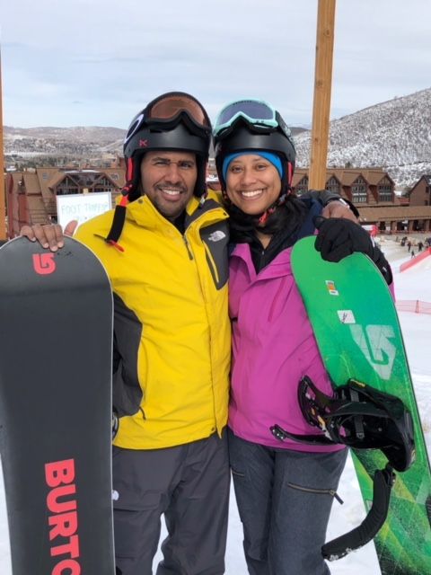 A man and a woman are posing for a picture while holding snowboards that say burton