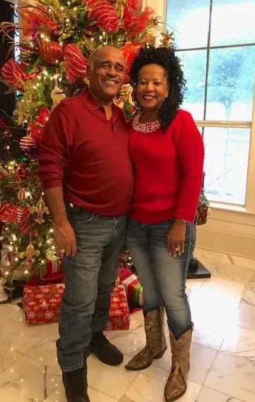 A man and a woman are posing for a picture in front of a christmas tree.