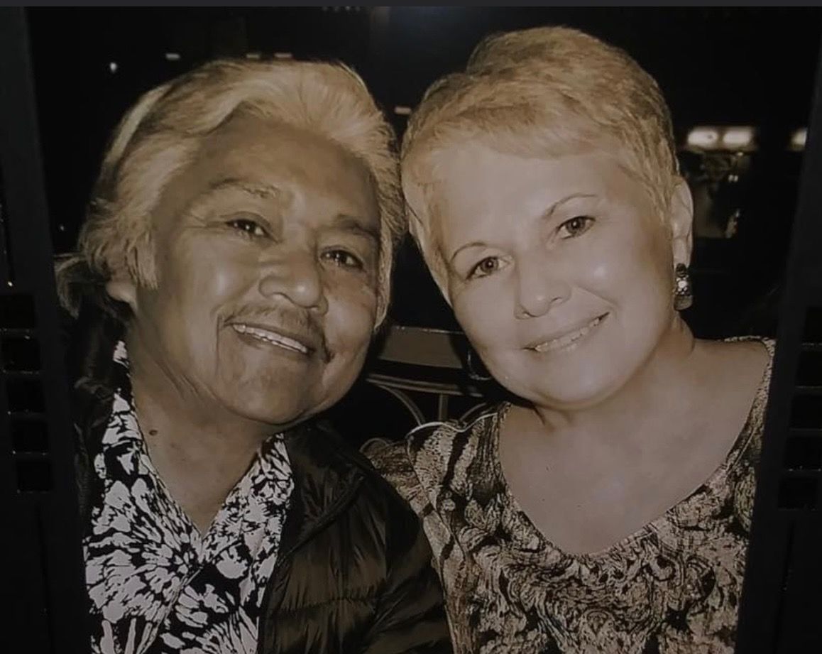 Two women are posing for a picture together and smiling for the camera.