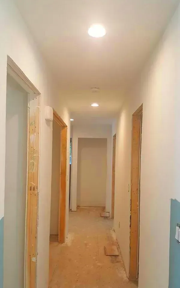 A long hallway with a lot of doors and a light on the ceiling.