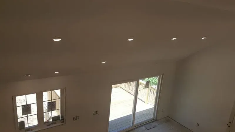 A living room with a sliding glass door and ceiling lights.