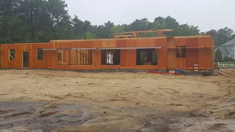 A large house is being built in a dirt field.