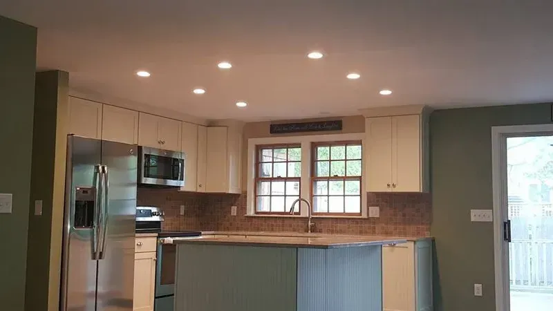 A kitchen with stainless steel appliances and green cabinets.