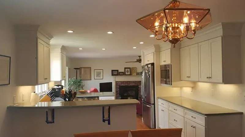 A kitchen with white cabinets and a chandelier hanging from the ceiling