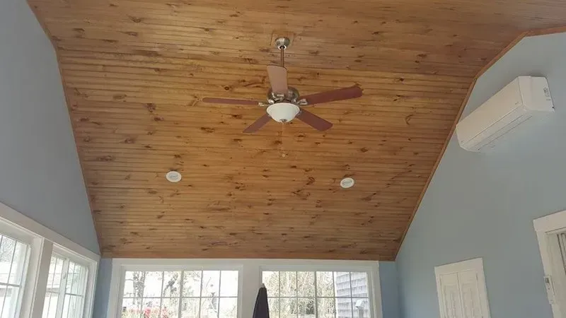 A room with a wooden ceiling and a ceiling fan