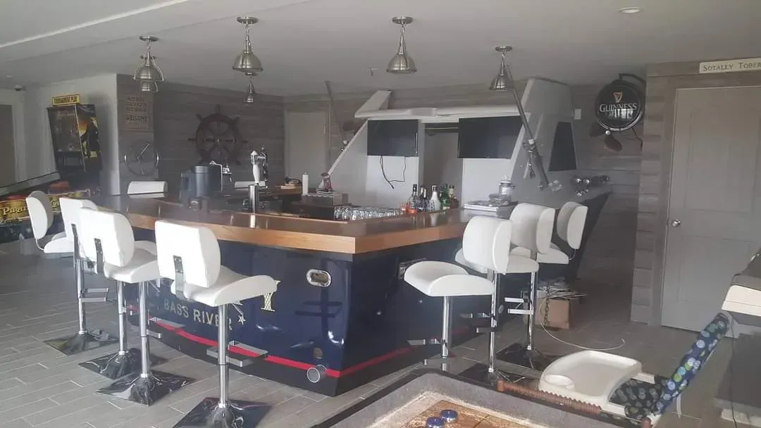 A large room with a bar and stools in it.