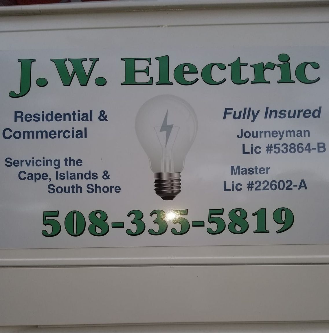 J.W. Electric sign with phone number, residential and commercial services, lightbulb graphic.
