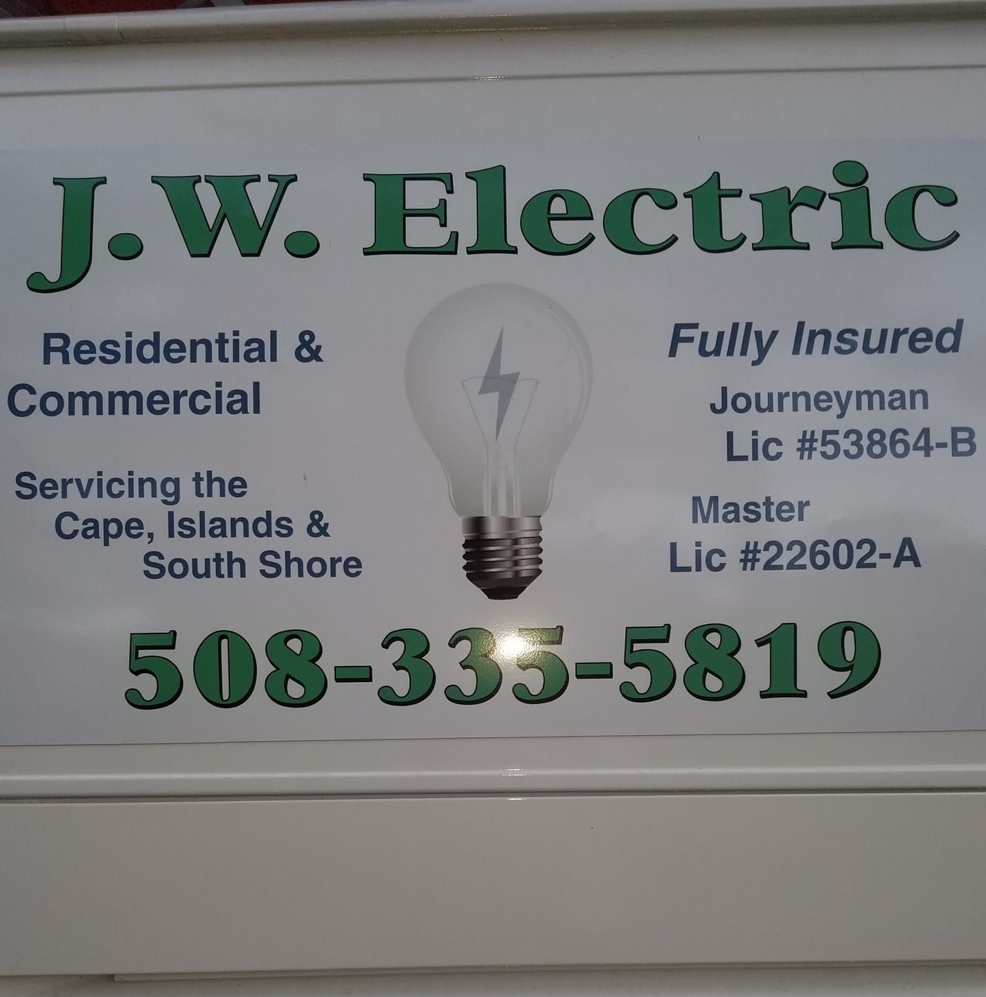 J.W. Electric sign with phone number, residential and commercial services, lightbulb graphic.