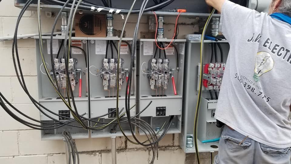 An electrician working on an electrical panel with wires. Outdoor setting.