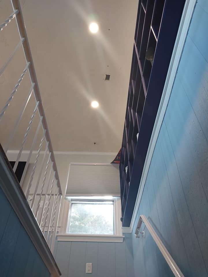 Stairwell with blue walls, white trim and railing, and a window. Ceiling has recessed lights.