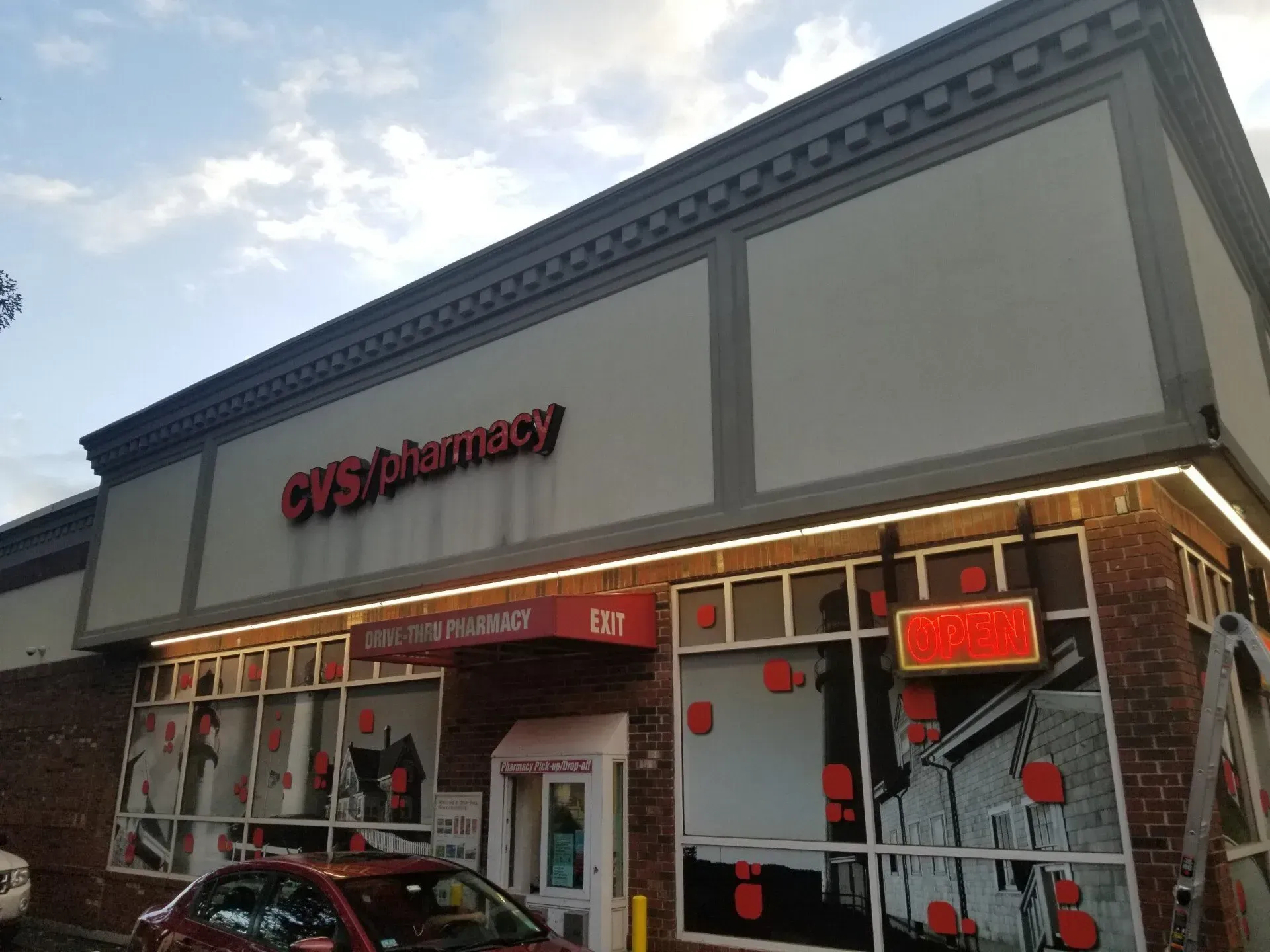 A cvs pharmacy with a red car parked in front of it.