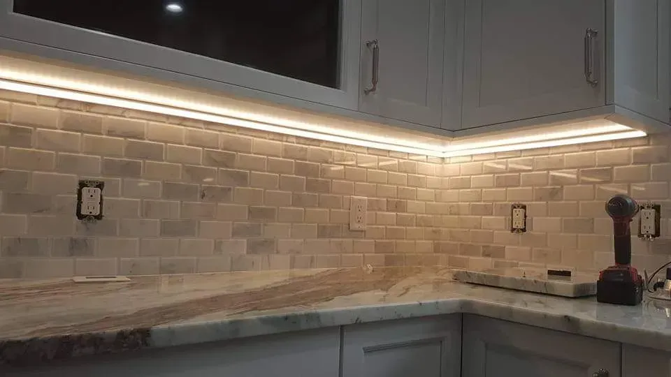 A kitchen with white cabinets and a drill on the counter.