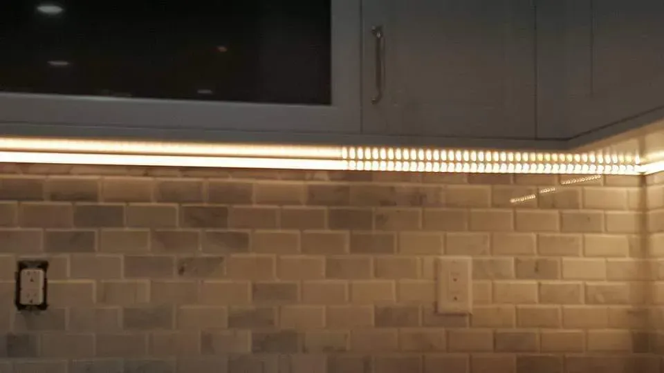 A kitchen with a brick wall and cabinets and a light on the wall.
