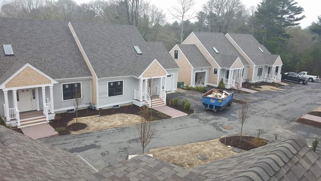 A row of houses with a blue dumpster parked in front of them.