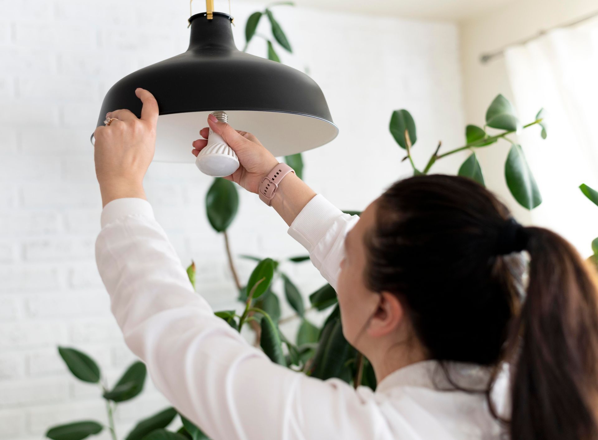A woman is changing a light bulb in a living room.